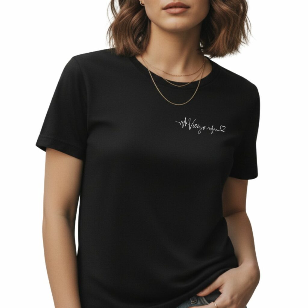 Pourquoi Whizaloo a choisi le minimalisme plutôt que le folklore Mockup d'un t-shirt noir à col rond porté par une femme. Sur la poitrine, côté gauche, figure impression blanche minimaliste affichant le mot 'Vierge' entrelacé dans une ligne de battement de cœur (ECG) se terminant par un petit cœur.