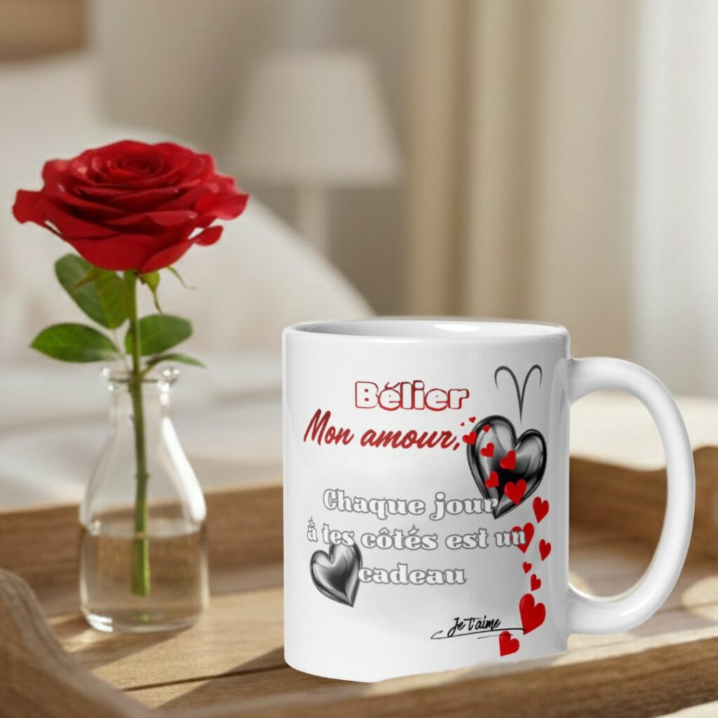 Mug Astro Personnalisé : Le Cadeau de Saint-Valentin Original et Romantique pour les Amoureux Mug blanc de la Saint-Valentin posé sur un plateau en bois à côté d'une rose rouge. Le mug affiche le texte en français "Belier Mon amour, Chaque jour à tes côtés est un cadeau" avec le symbole astrologique Bélier et des motifs de cœurs rouges et noirs.