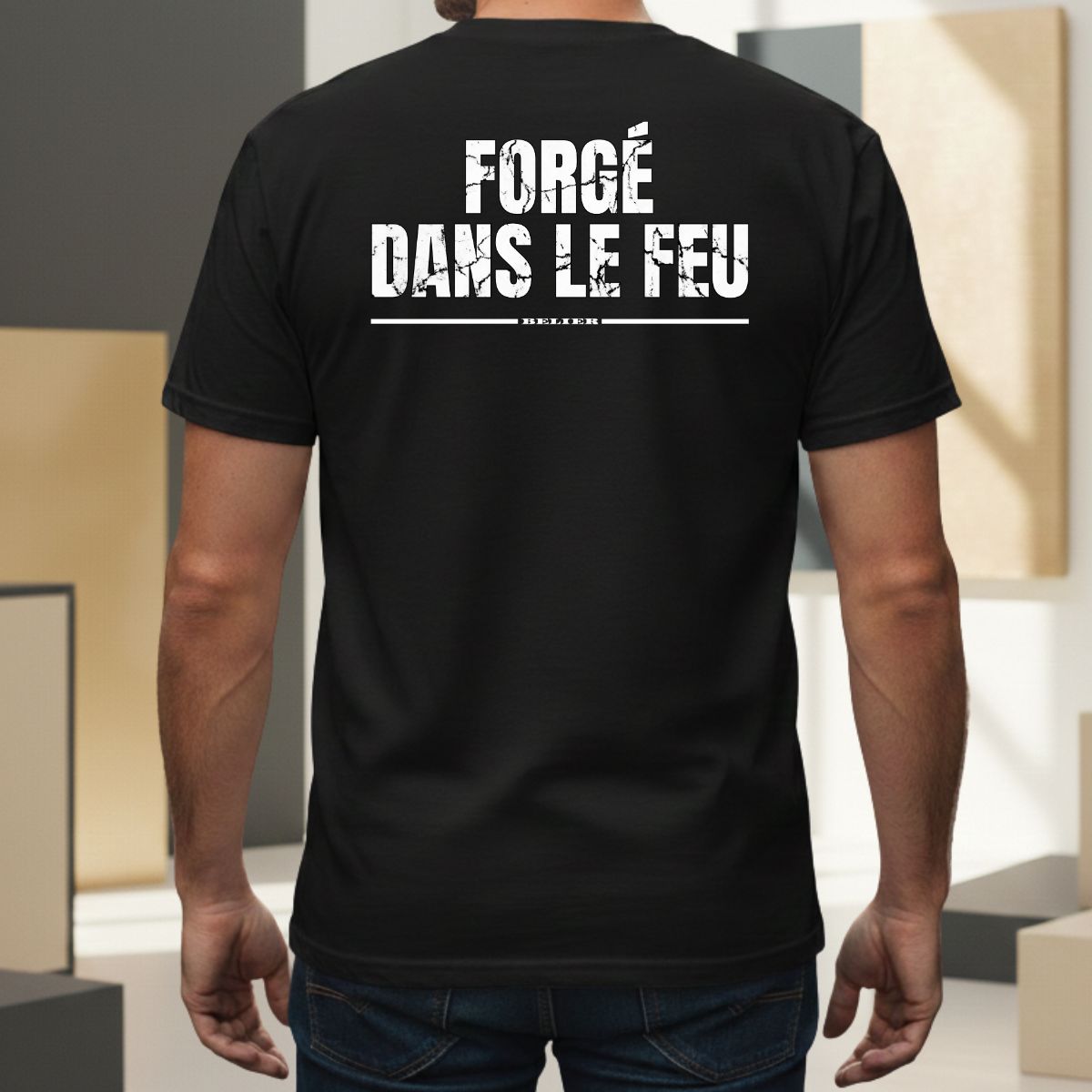 T-shirt Manches Courtes | Forgé dans le Feu | Bélier : Élément FEU T-shirt noir pour homme avec mention 'bélier' soulignée. Design graphique au style usé/vintage centré dans le dos, porté par un modèle masculin dans un cadre extérieur moderne.