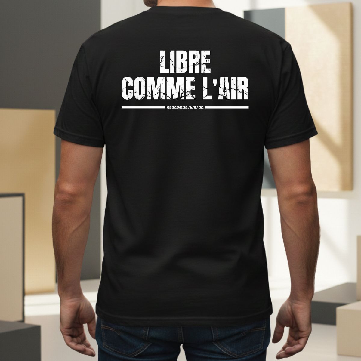 T-shirt Manches Courtes | Libre comme l’Air | Gémeaux : Élément Air T-shirt noir pour homme avec mention 'gémeaux' soulignée. Design graphique au style usé/vintage centré dans le dos, porté par un modèle masculin dans un cadre extérieur moderne.
