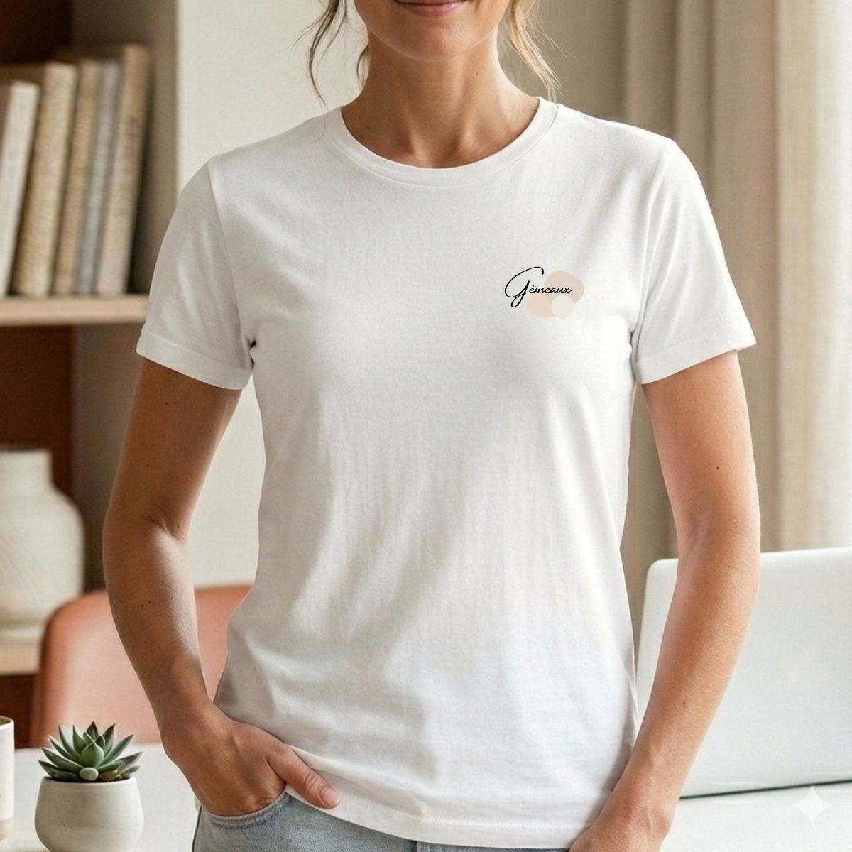 T-shirt Bohème Chic Zen Minimaliste – Signe Gémeaux & Formes Abstraites Une femme portant un T-shirt blanc minimaliste avec le mot « Gémeaux » inscrit en cursive noire sur la poitrine, accompagné de formes abstraites beiges et neutres.